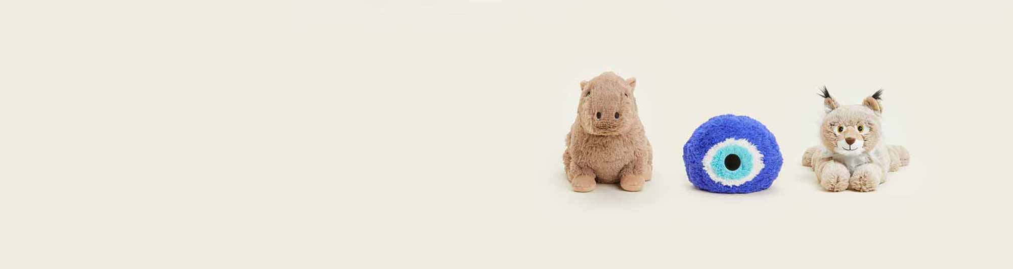 A Capybara Warmies, Blue Evil Eye Warmies, and a Bobcat Warmies sitting in a row