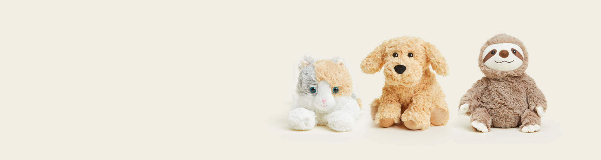 A Calico Cat Warmies, Golden Dog Warmies and Sloth Warmies sitting in a row.