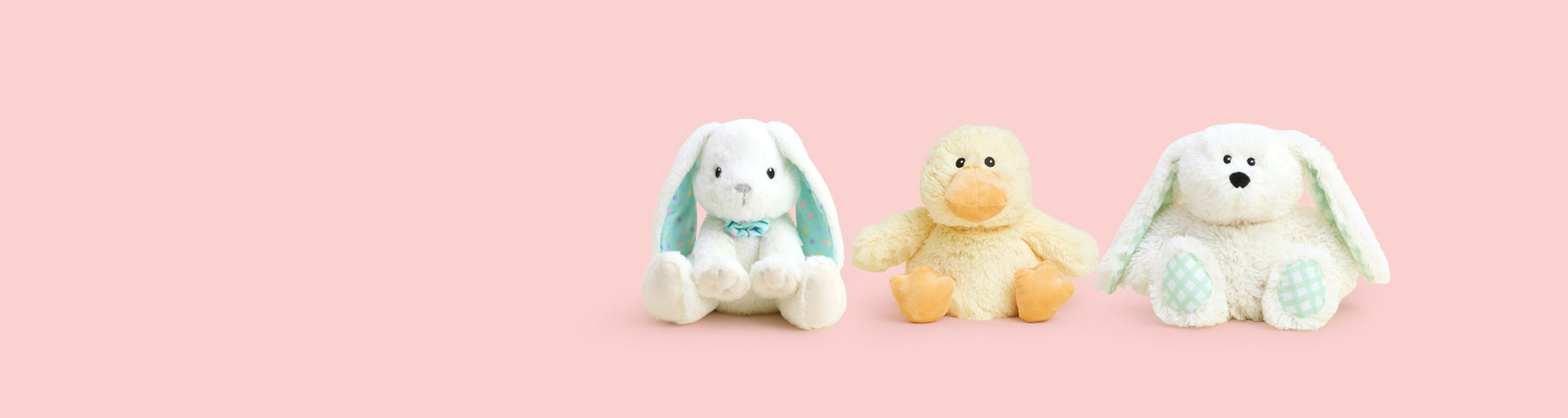Pink Bunny, Brown Bunny and Chick Warmies sitting in a row against a purple background decorated with colorful easter eggs.