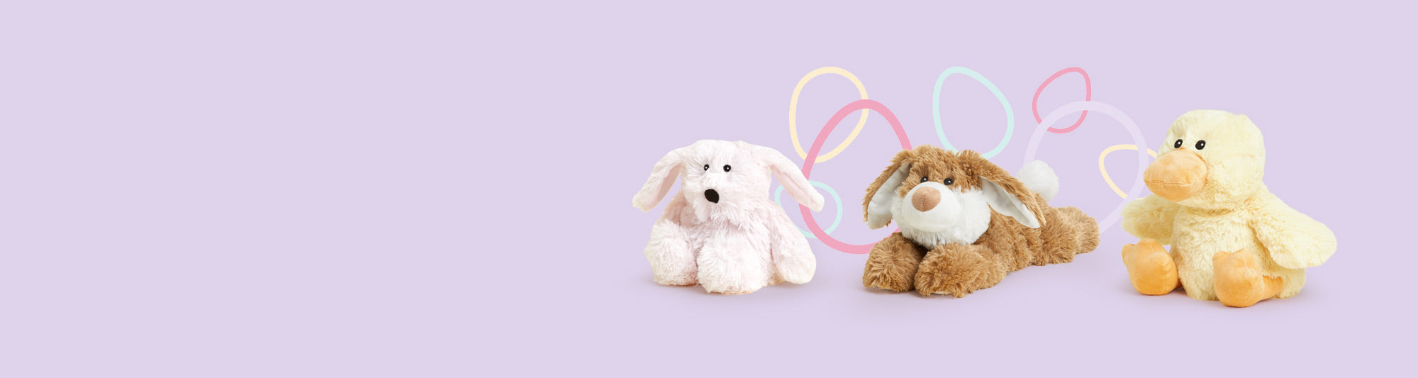 Pink Bunny, Brown Bunny and Chick Warmies sitting in a row against a purple background decorated with colorful easter eggs.