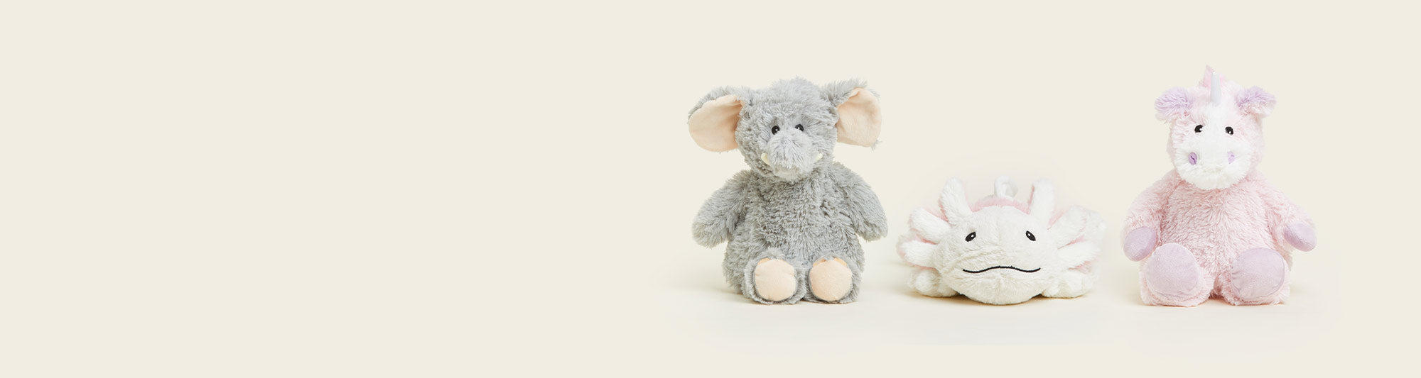 Gray Elephant Warmies, Axolotly Warmies, and Pink Unicorn Warmies sitting in a row