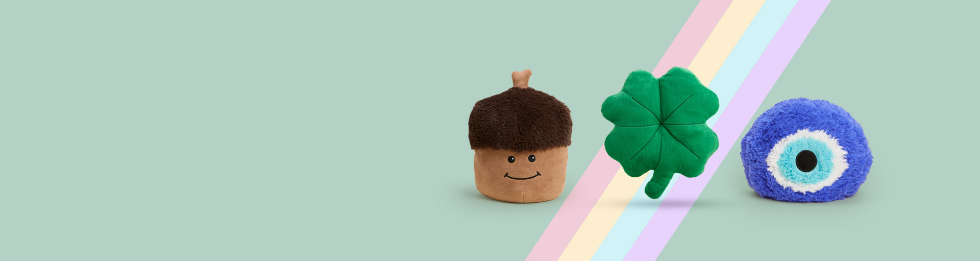 Frog, Caterpillar and Dinosaur Warmies sitting in a row against a green background.