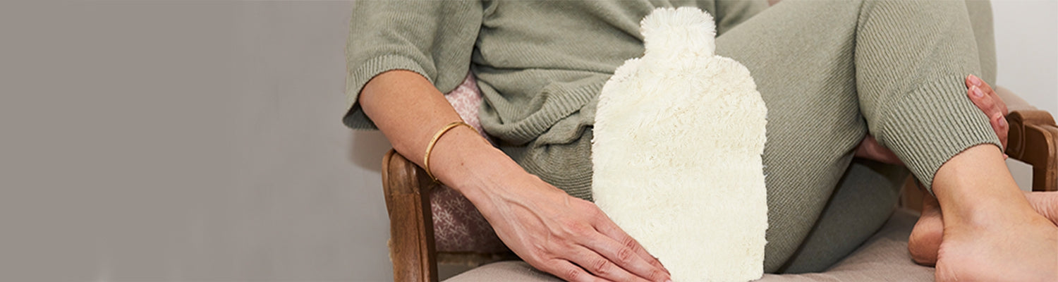 A person's hand holding the Cream Warmies Bottle.