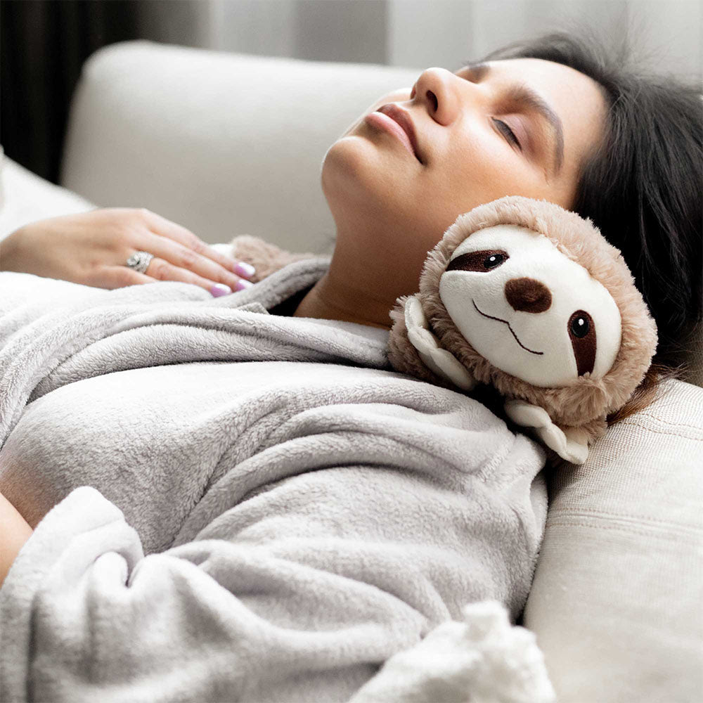 woman resting with lavender scented sloth stuffed animal warmies