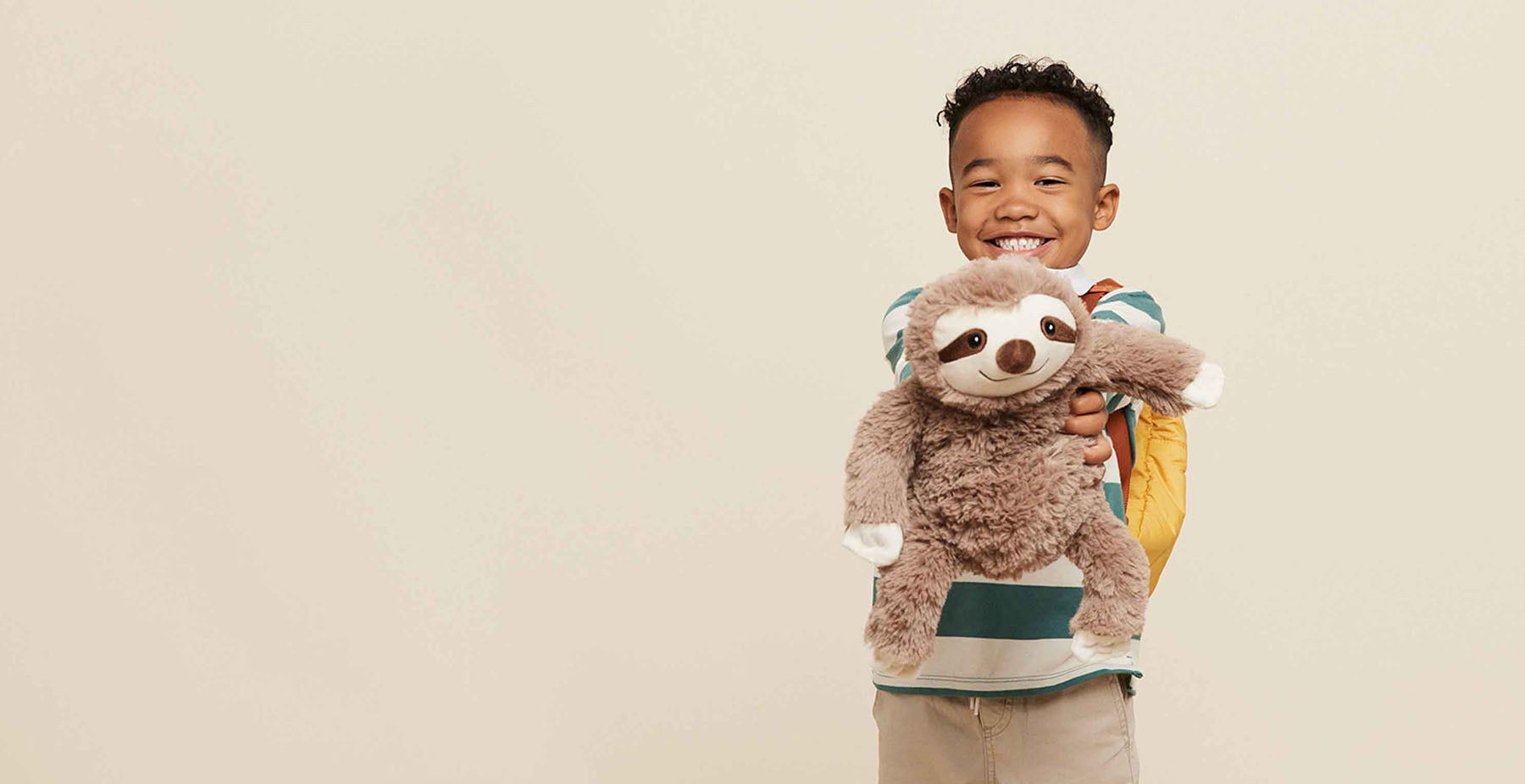 boy holding sloth stuffed animal warmies