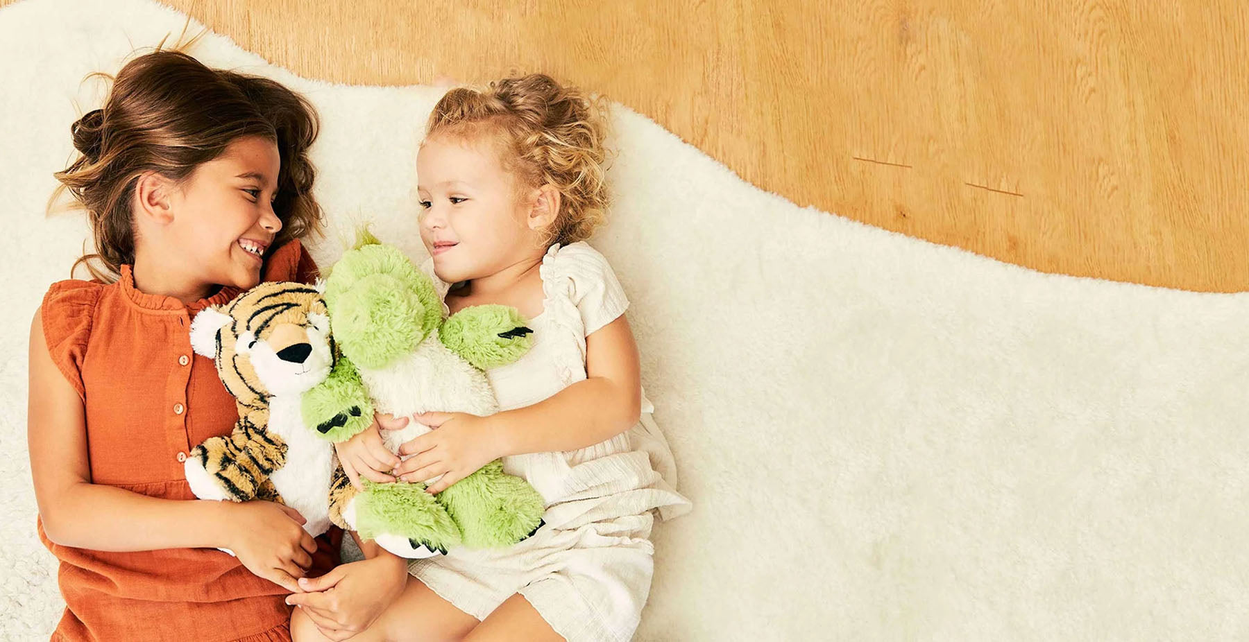 girls playing with tiger and green dinosaur stuffed animal warmies