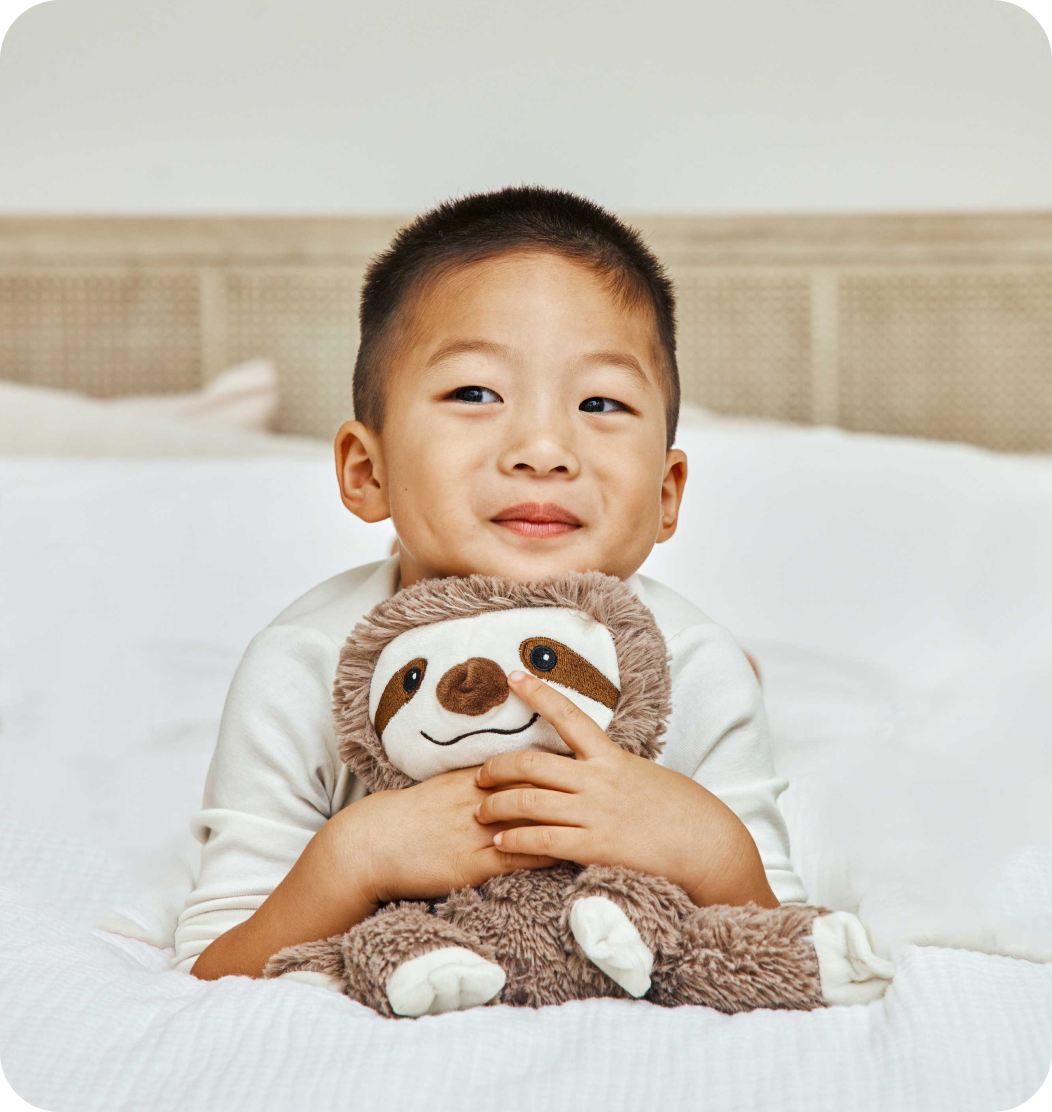 Young boy snuggling with his Sloth Warmies.