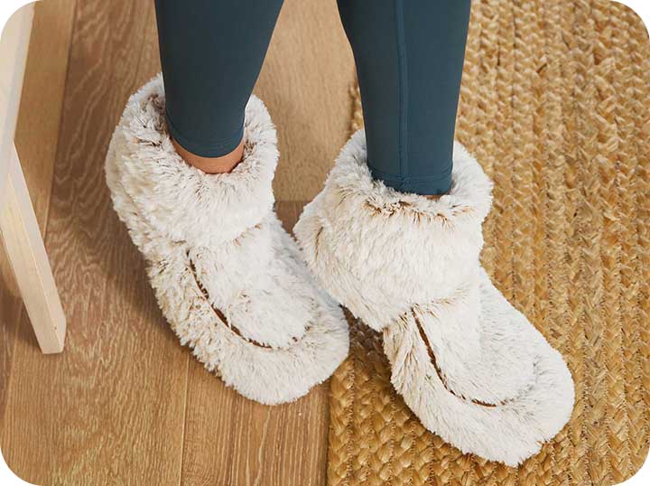 A close up shot of a person wearing the Warmies Marshmallow Brown slippers.