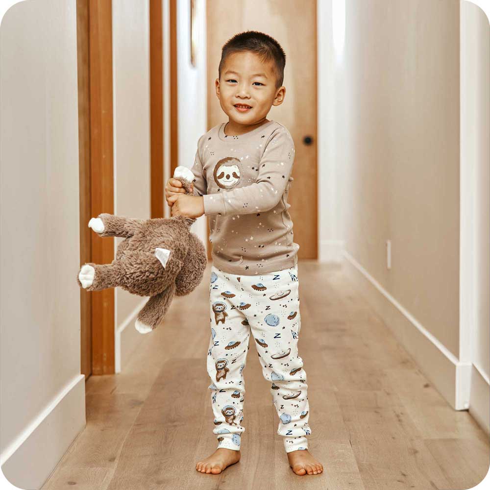 Child playing with Plush Warmies Stuffed Animal while wearing Sloth Pajamas - Warmies USA