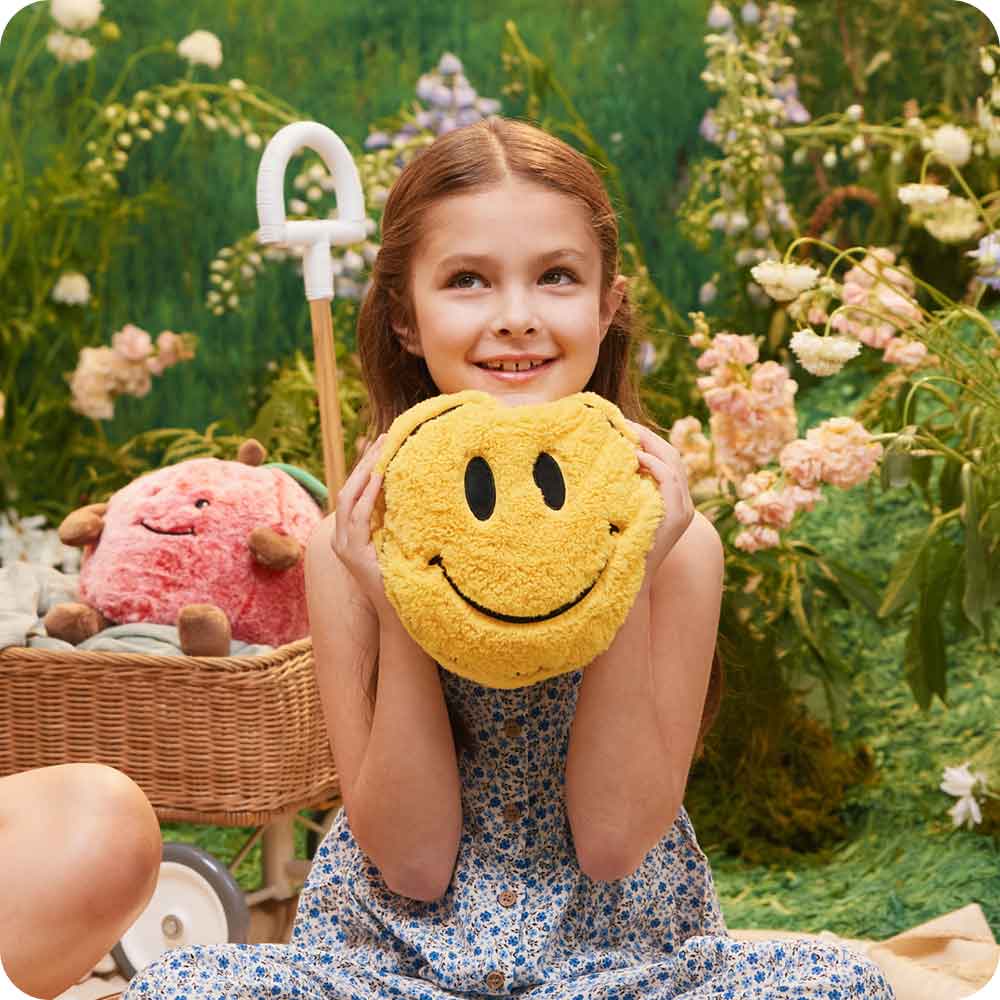 Girl holding and playing with Cute Weighted Lavender Scented Smiley Face Stuffed Animal Heating Pad Warmies