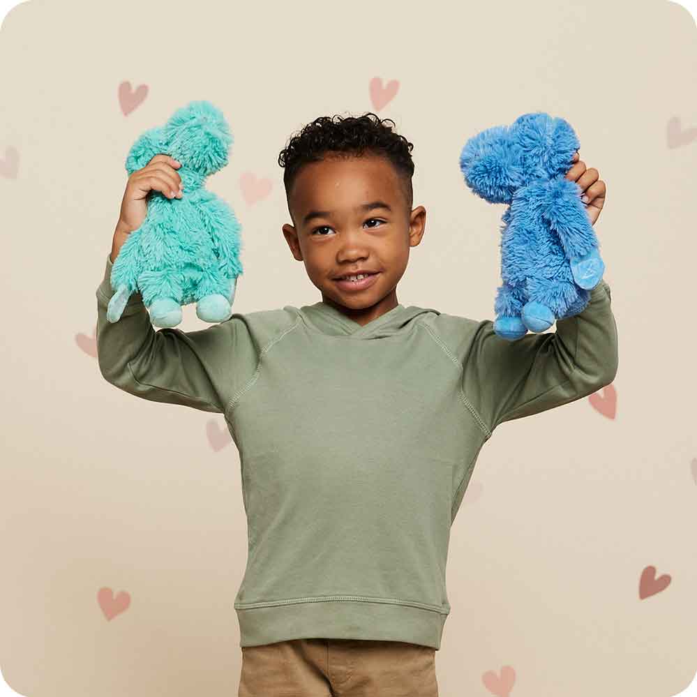 Boy raising his hands and holding Cute Weighted Lavender Scented Dinosaur Hugs Stuffed Animal Heating Pad Warmies