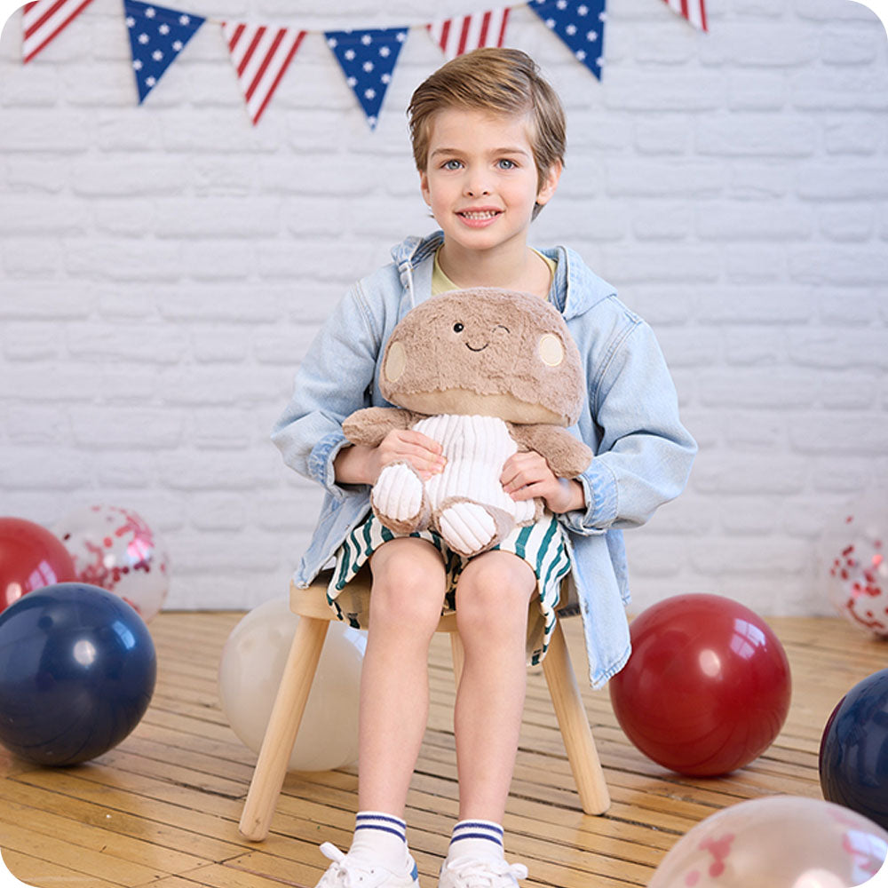 boy holding brown mushroom stuffed animal warmies