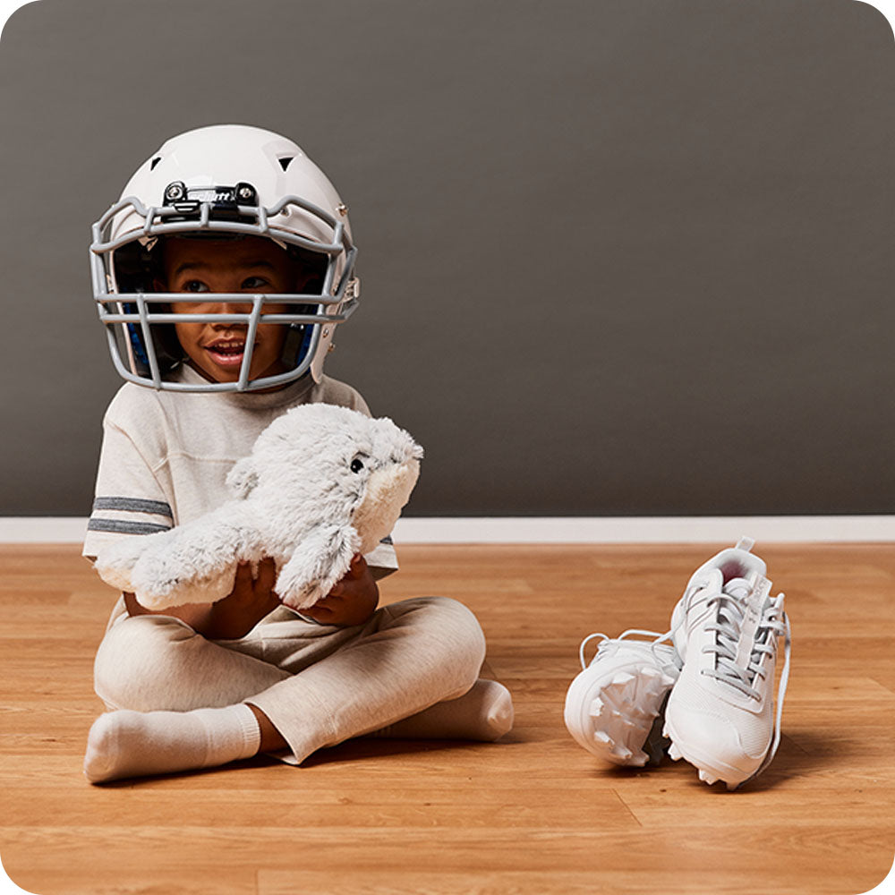 boy in football outfit holding dolphins stuffed animal