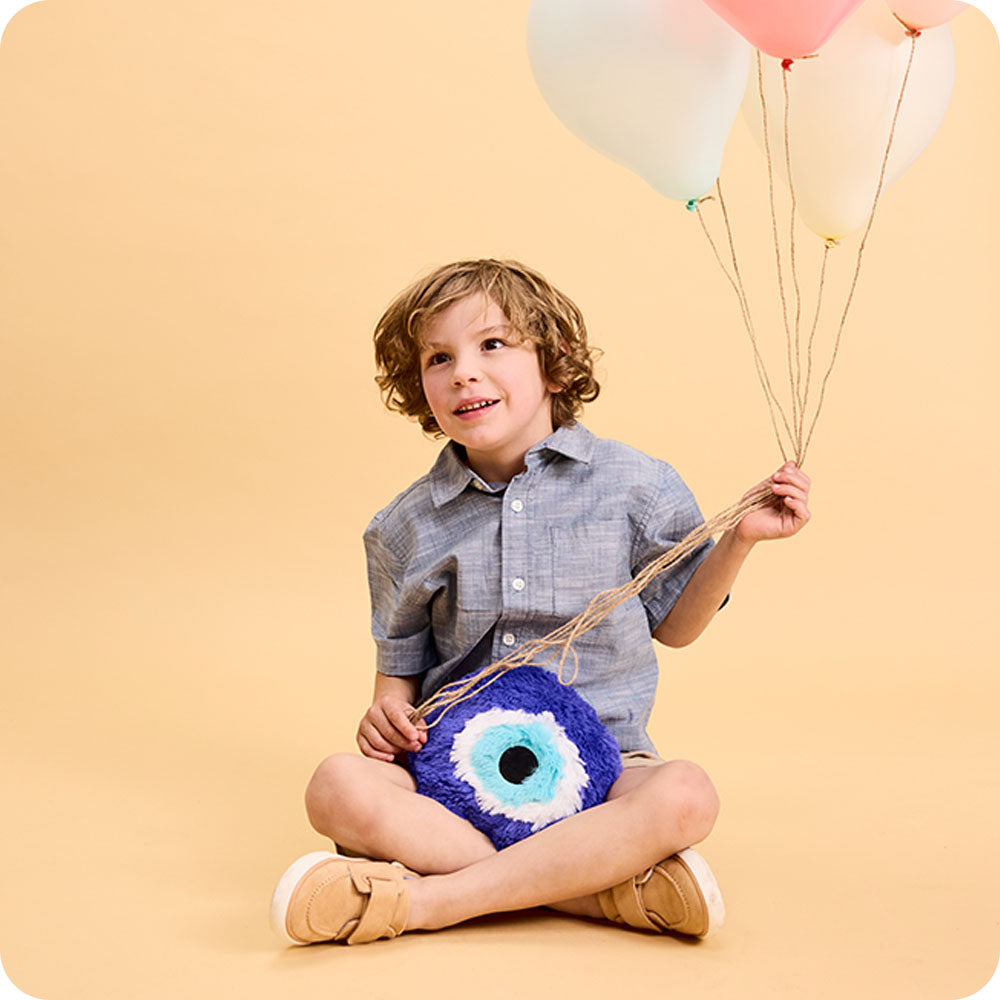 boy holding evil eye stuffed animal warmies