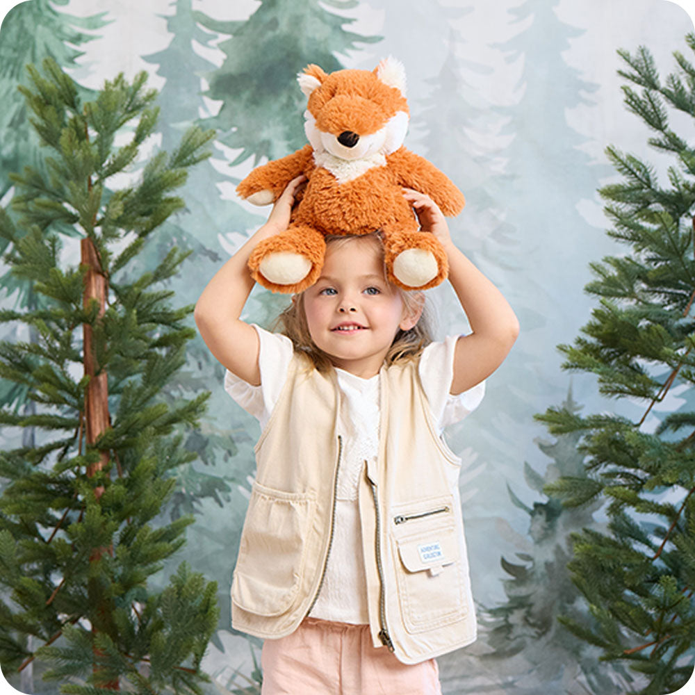 woodland scene with girl holding a fox stuffed animal on her head