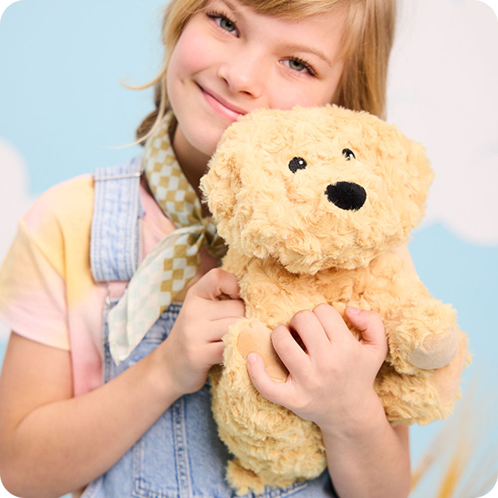 girl holding golden dog warmies stuffed animals