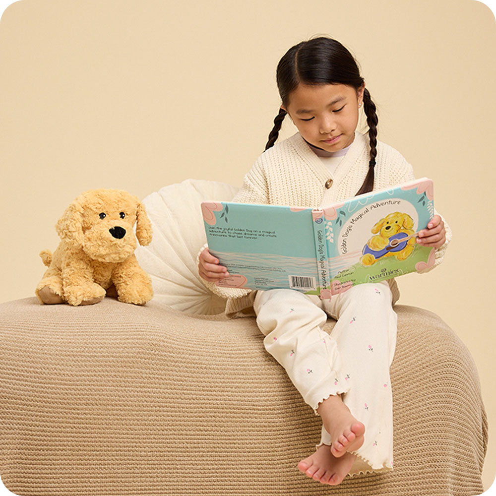 girl reading Golden Dog's Magical Adventure warmies book with golden dog stuffed animal at her side