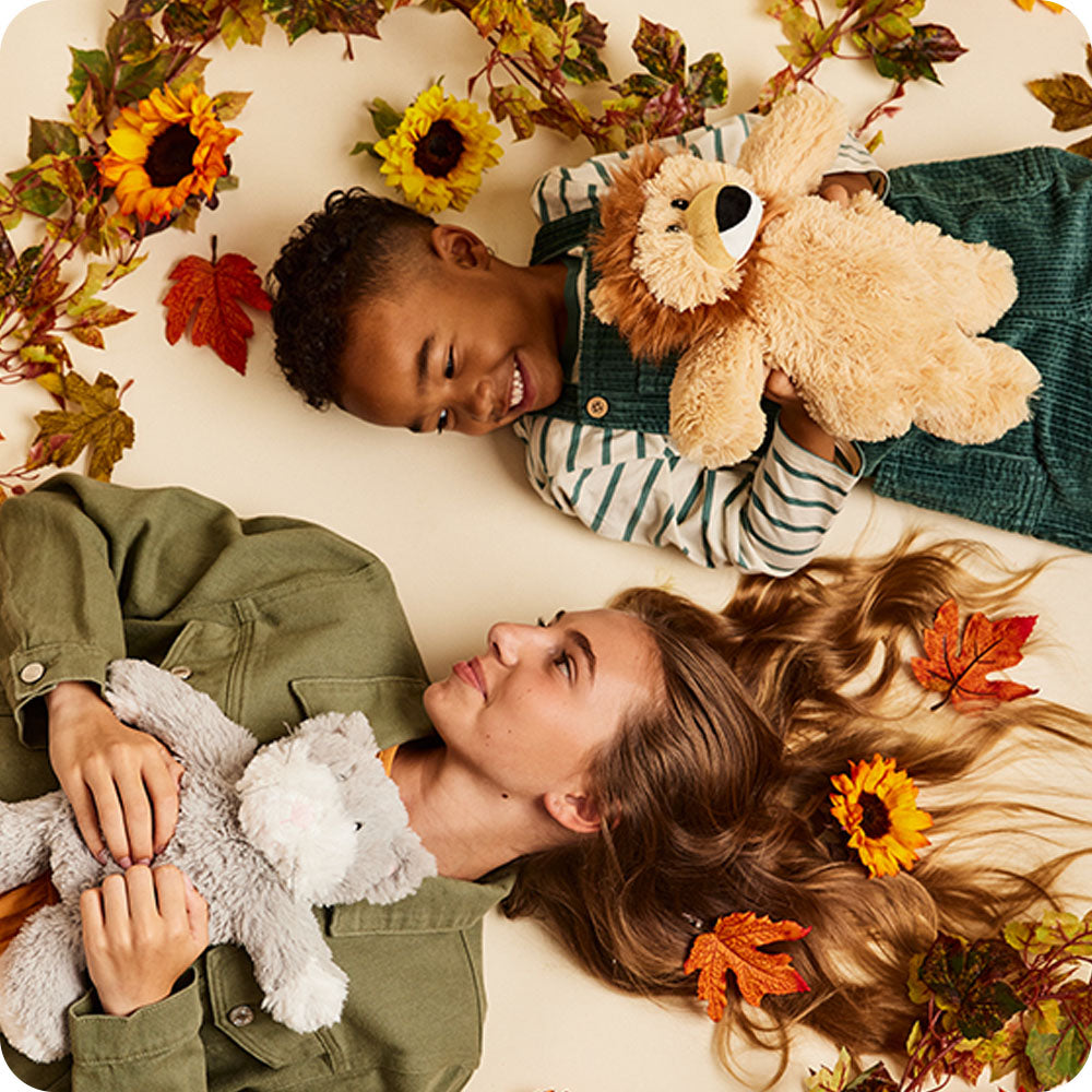 kids holding cat and lion warmies stuffed animals
