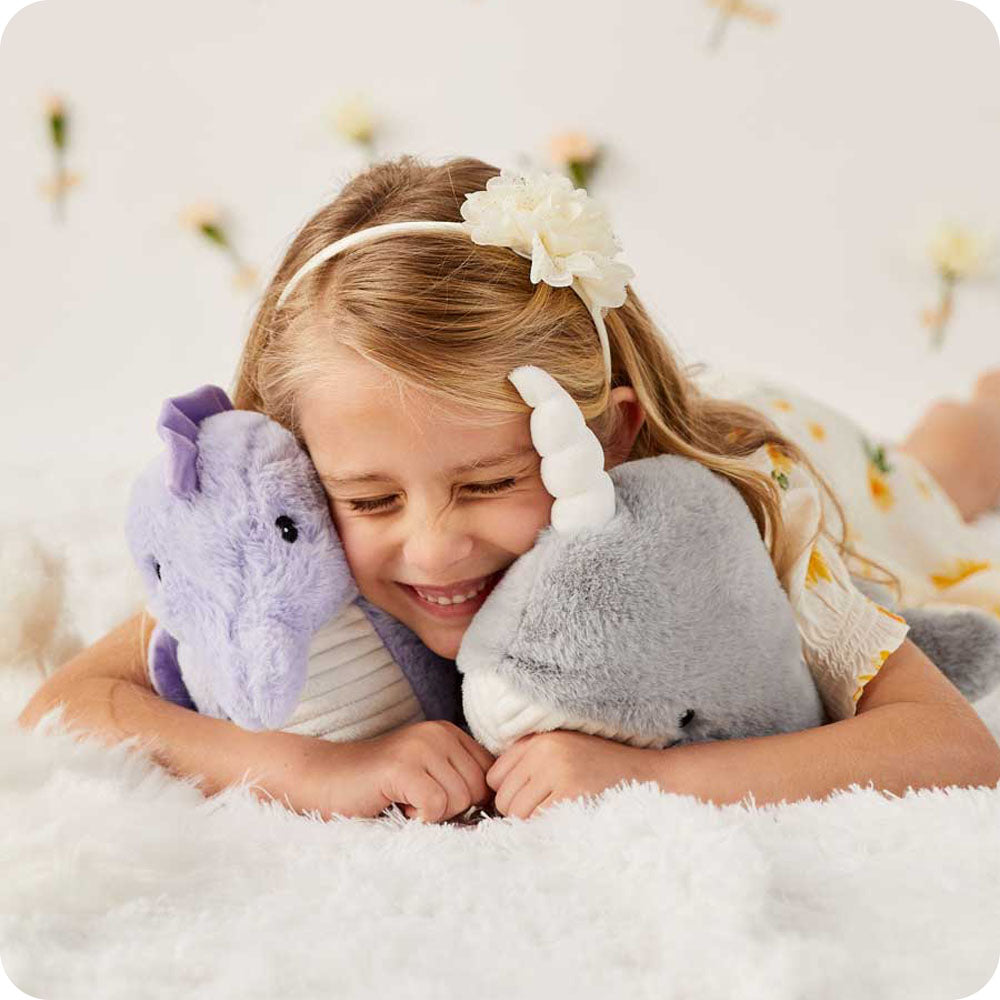 girl cuddling seahorse and narwhal stuffed animals