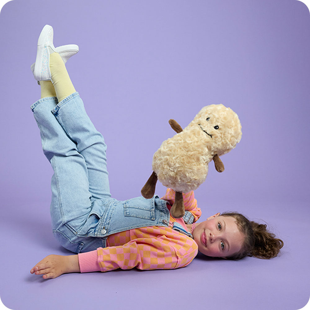 girl holding up a peanut stuffed animal warmies