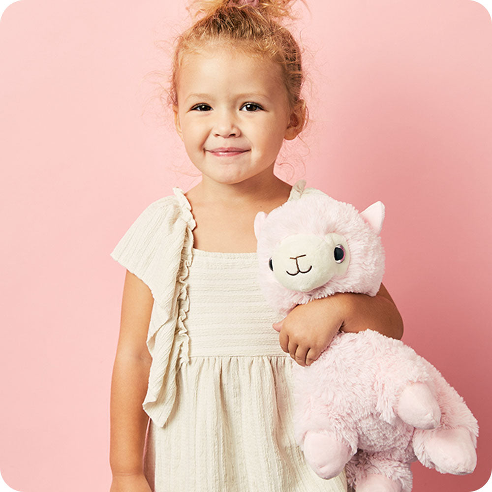 girl holding a warmies pink llama stuffed animal