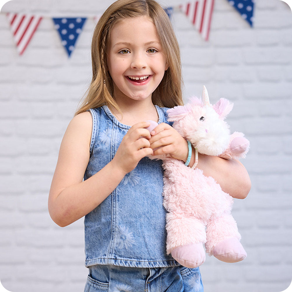 girl holding pink unicorn stuffed animal warmies