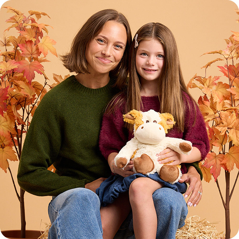 mother and daughter hugging pumpkin spice cow stuffed animal