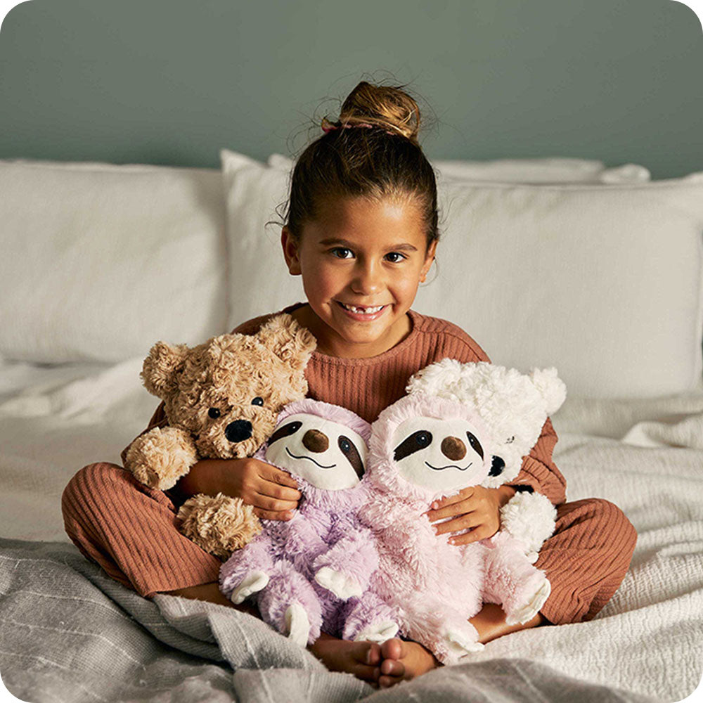 little girl hugging sloth stuffed animal warmies