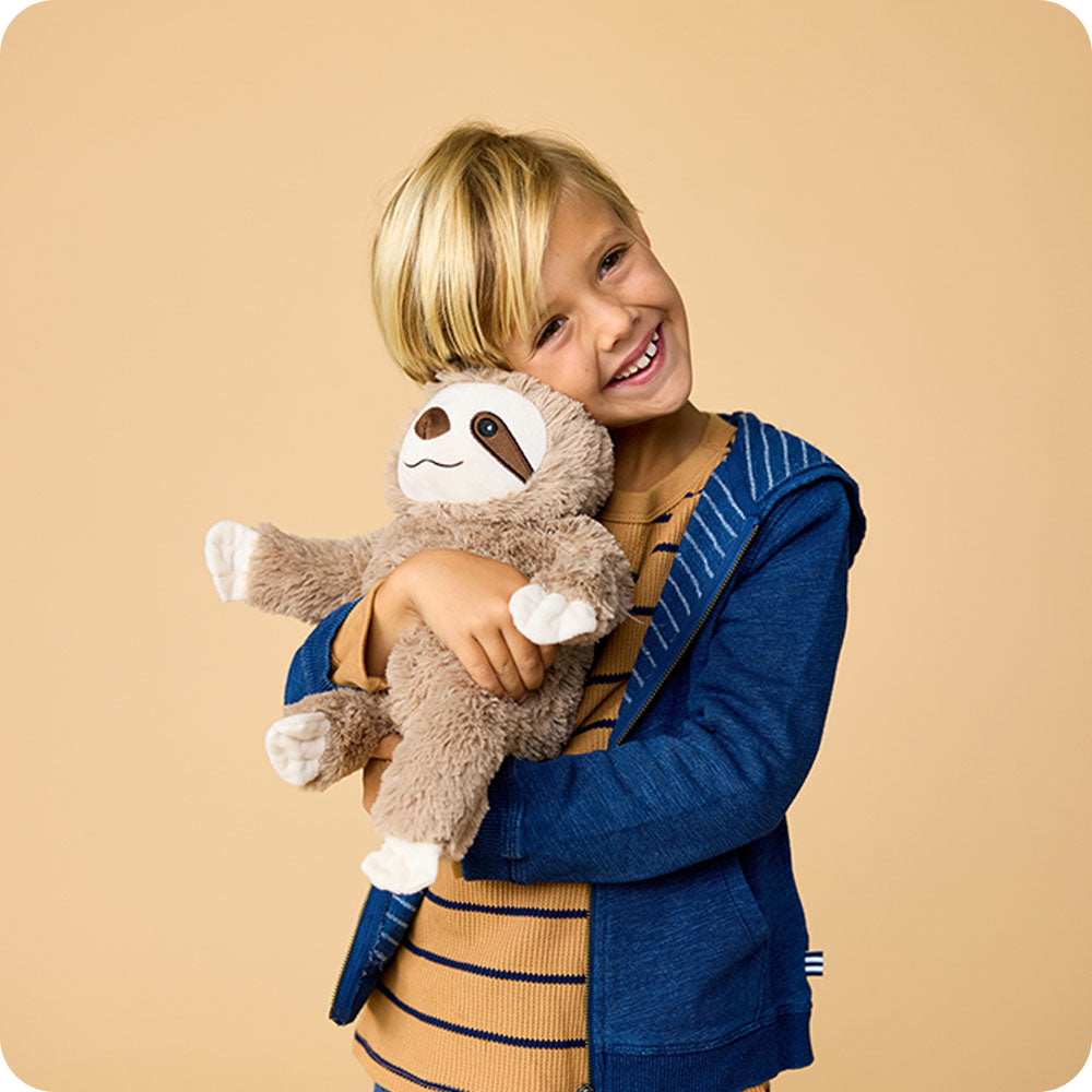 little boy hugging sloth stuffed animal warmies