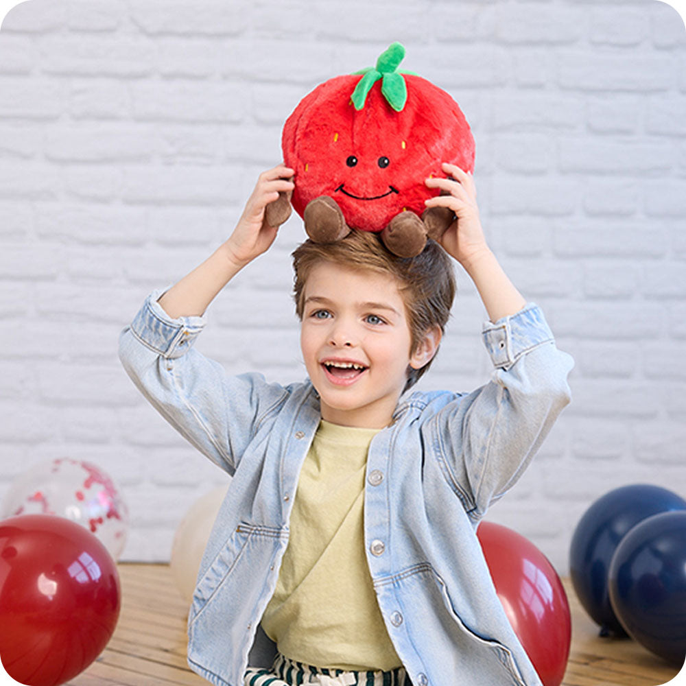 boy holding strawberry stuffed animal warmies on his head