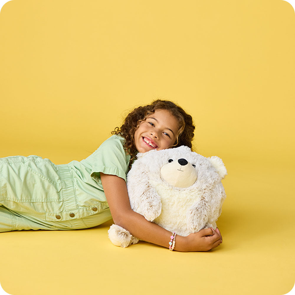 girl hugging supersized bear stuffed animal on yellow background
