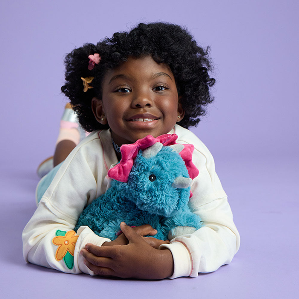 girl hugging triceratops stuffed animal warmies