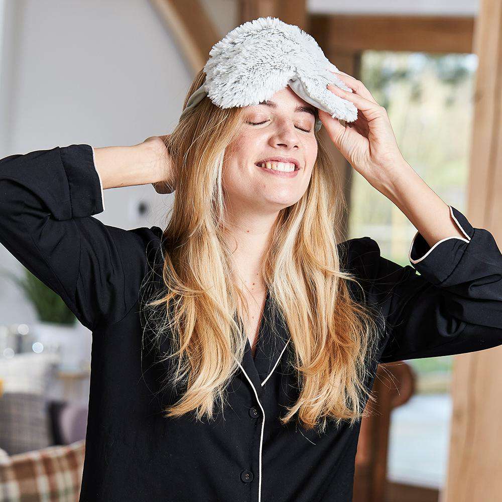 Woman smiling while wearing Microwavable Marshmallow Eye Mask: Cozy comfort for serene relaxation.