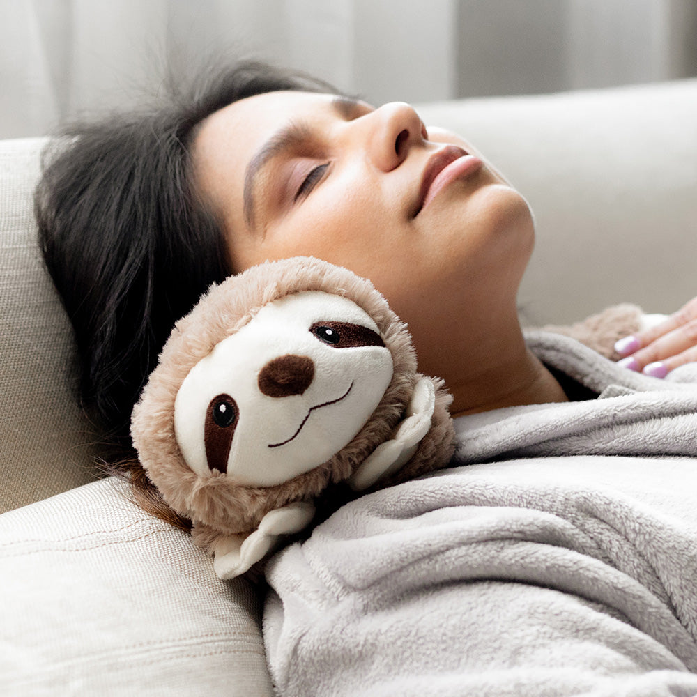 Woman sleeping and relaxing while wearing Sloth Wrap Stuffed Animal Warmies