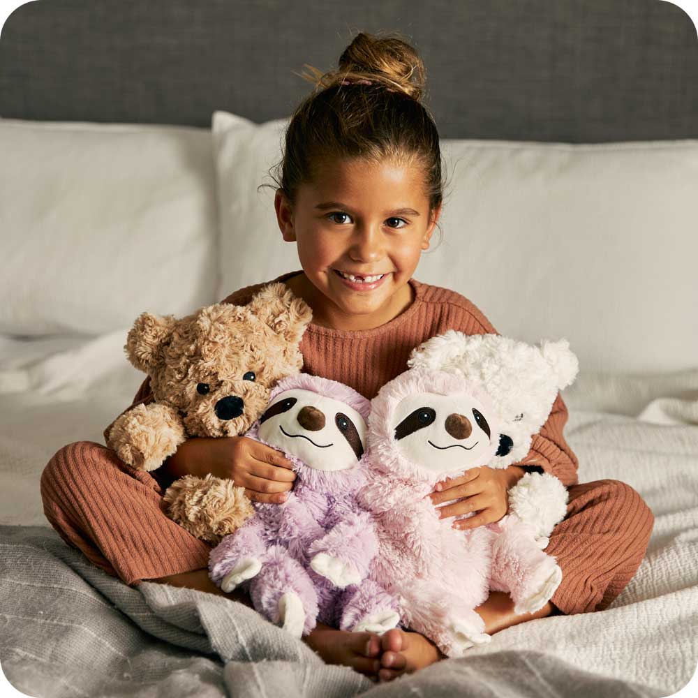 Little girl holding many Cute Weighted Lavender Scented Pink Sloth Stuffed Animal Heating Pad Warmies