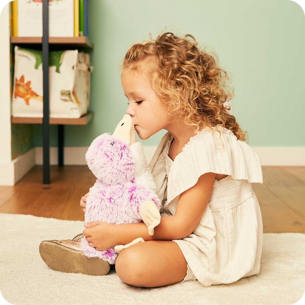 Toddle sitting down holding a Soft Lavender Scented Platypus Warmies