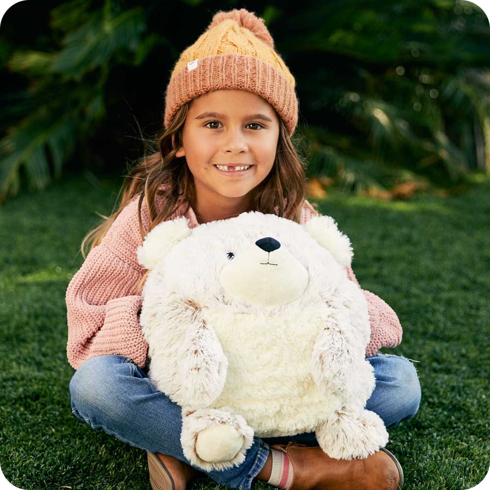 Girl smiling while holding in her lap a Cute Weighted Lavender Scented Supersized Bear Stuffed Animal Heating Pad Warmies