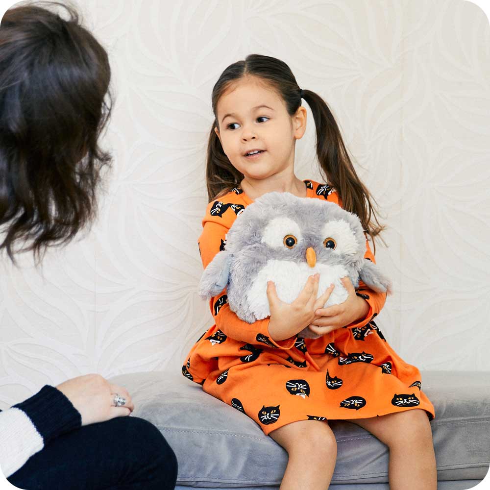 Child hugging a Soft Warm Weighted Owl Plush Warmies
