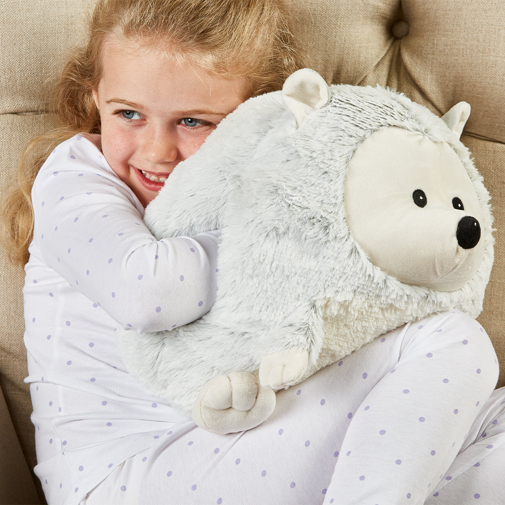 Girl smiling while holding Microwavable Comforting Supersized Hedgehog Warmies