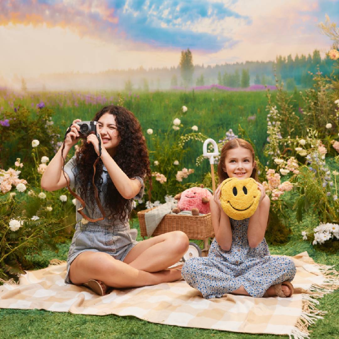 Two teens sitting in a field with Warmies stuffed animals.