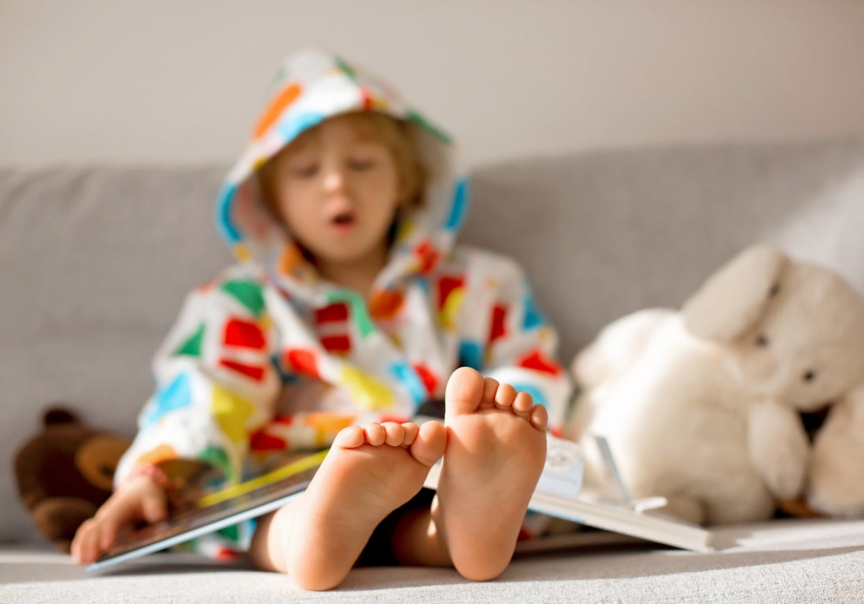 Kid on couch with plush stuffed animals. 