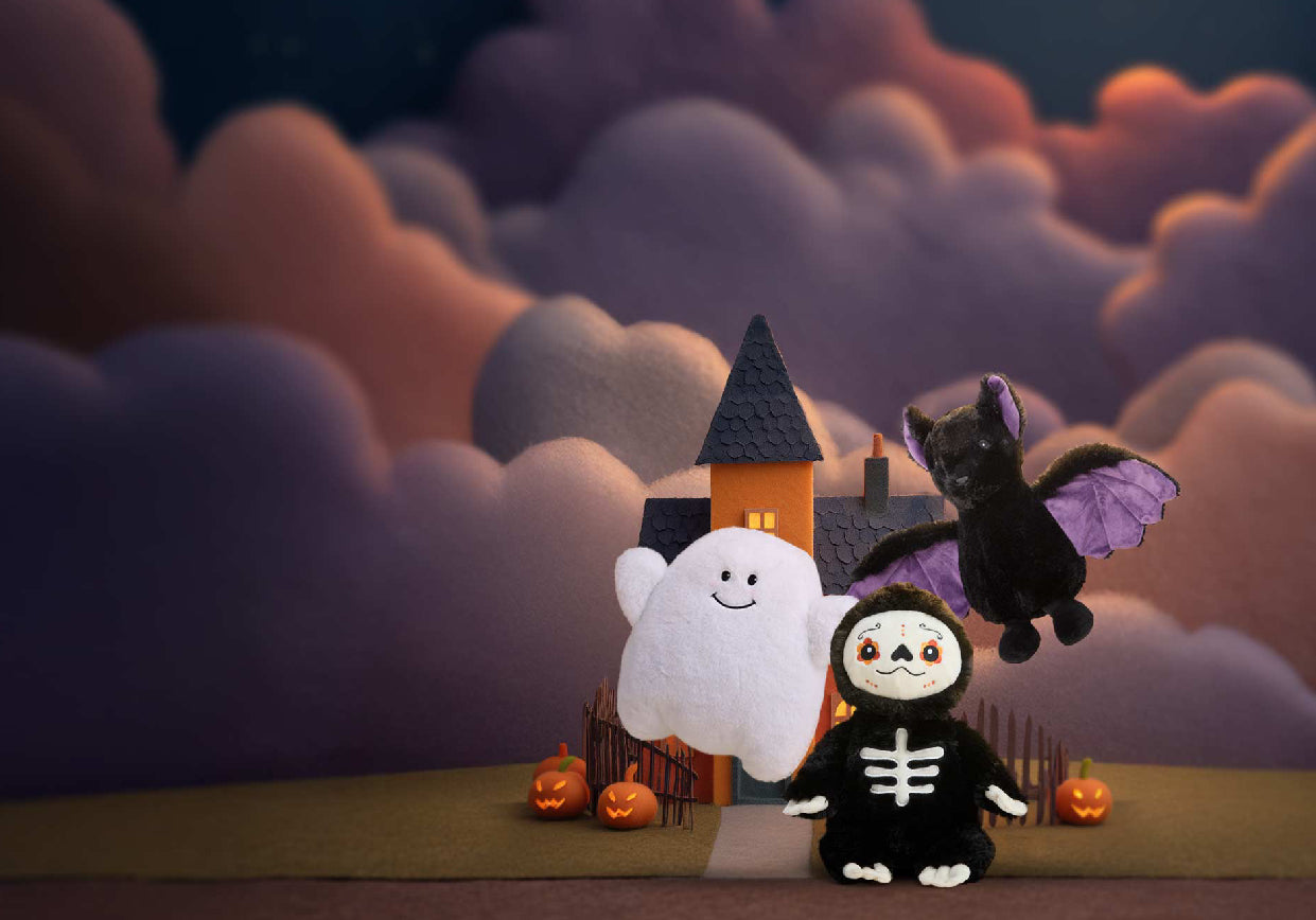 Spooky Ghost, Day of the Dead, Purple Wing Bat Warmies in front of a haunted house and clouds.