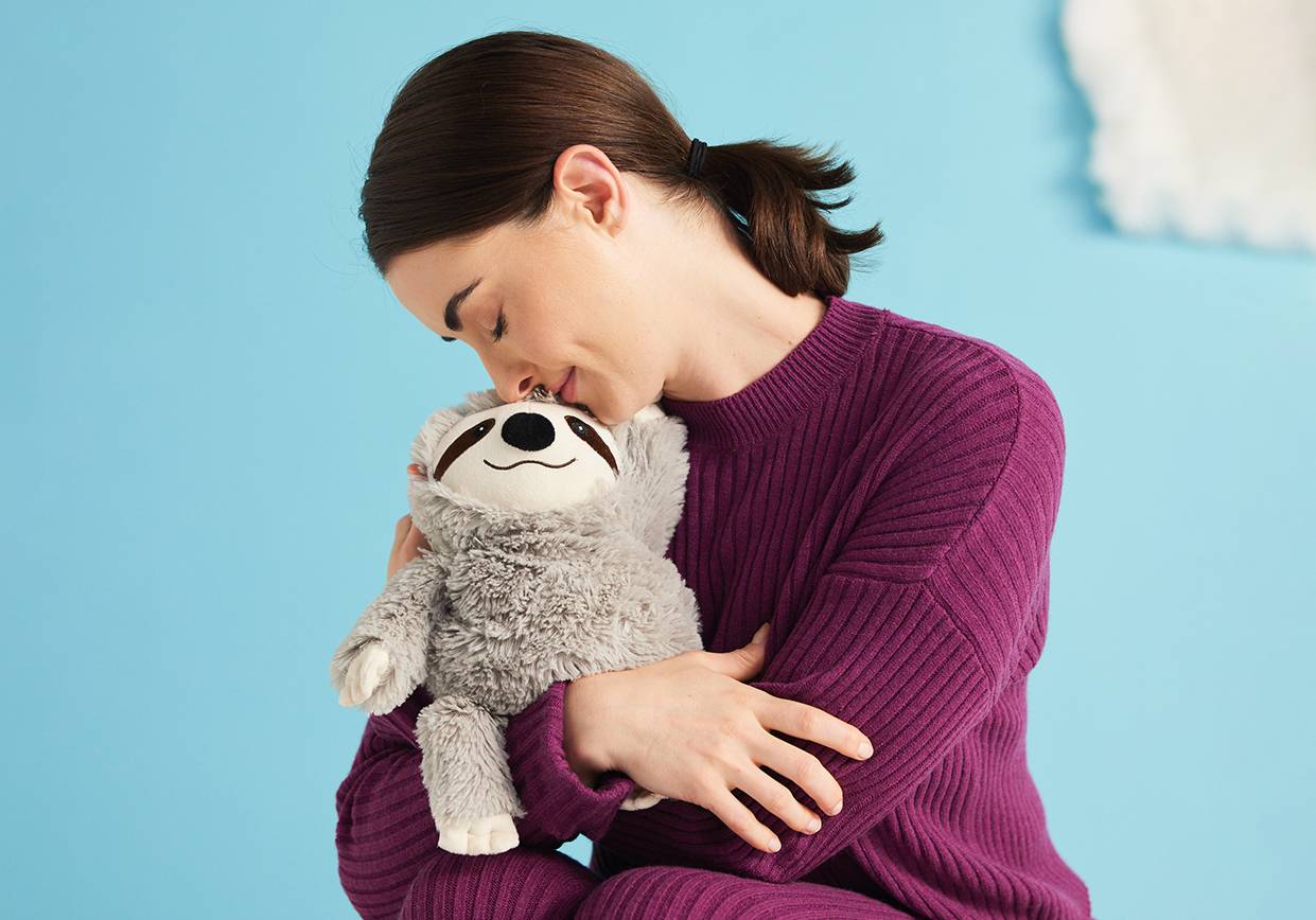 A woman hugging a Gray Sloth Warmies