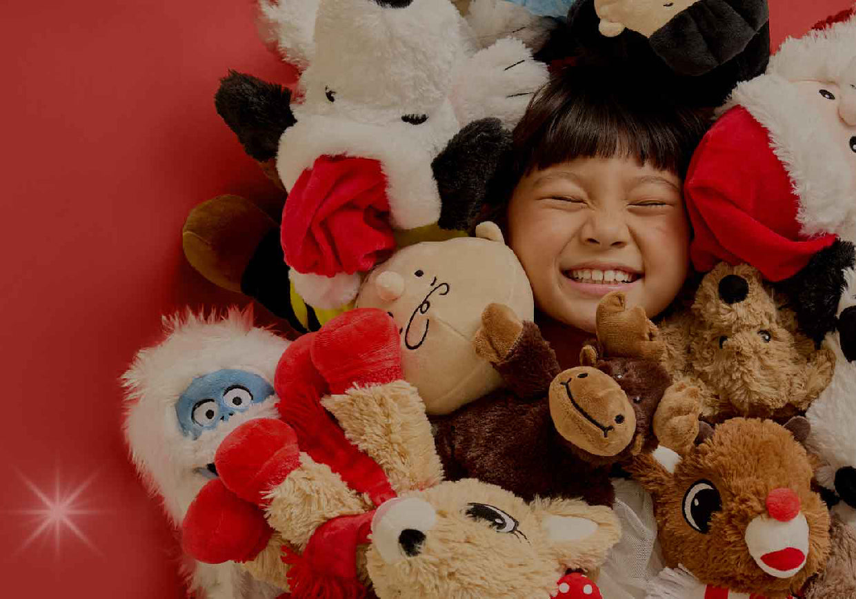 Girl on red background with Bumble, Charlie Brown, Rudolph, Clarice and Snoopy With Santa Hat Warmies.