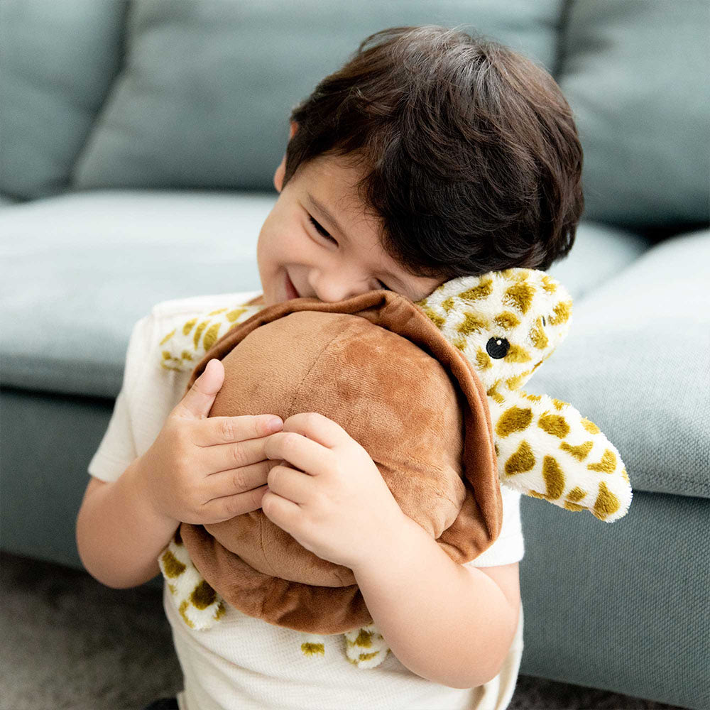 boy hugging turtle stuffed animal warmies