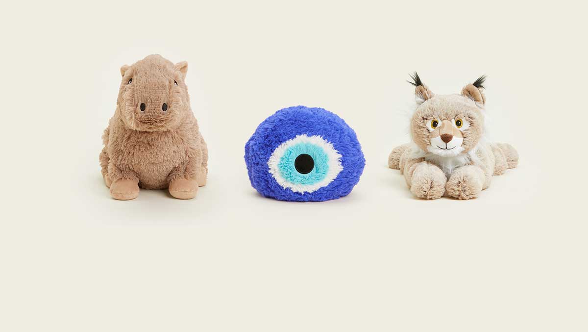 A Capybara Warmies, Blue Evil Eye Warmies, and a Bobcat Warmies sitting in a row