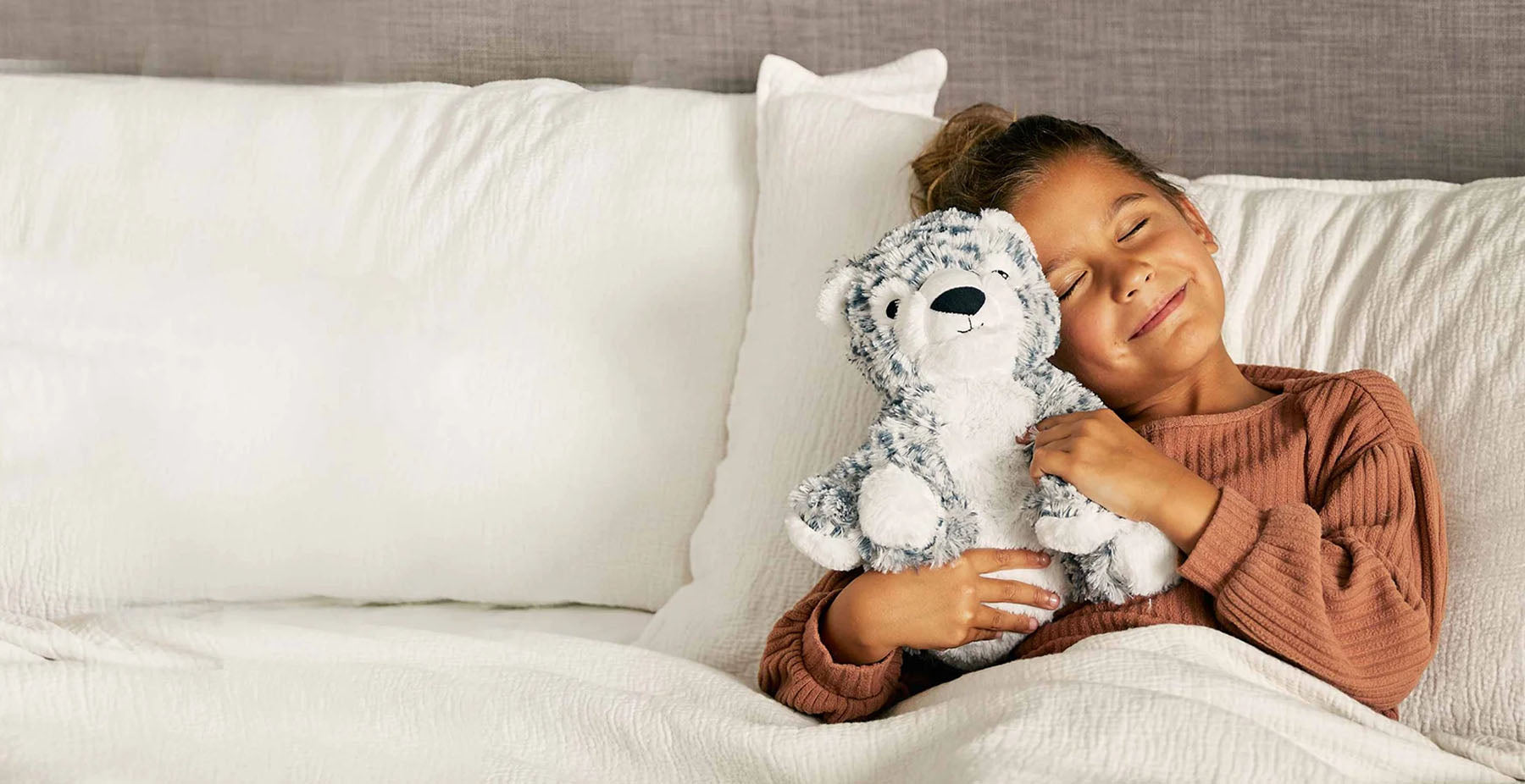girl hugging snow leopard stuffed animal warmies
