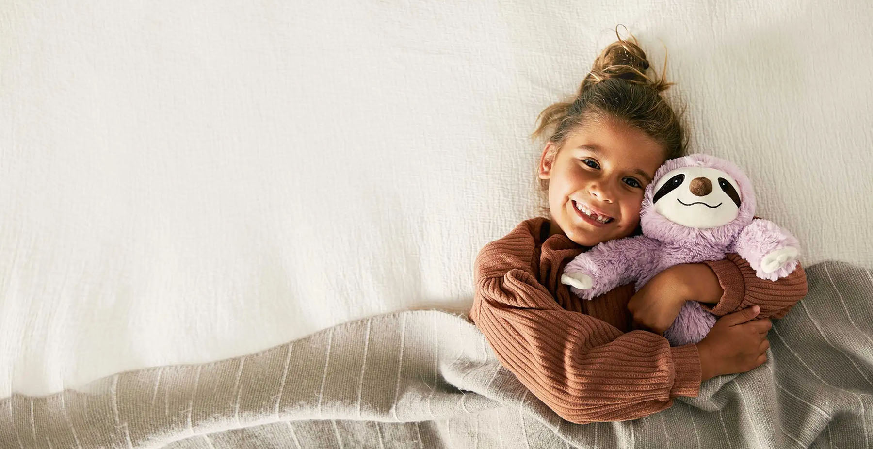 girl hugging pink sloth stuffed animal warmies