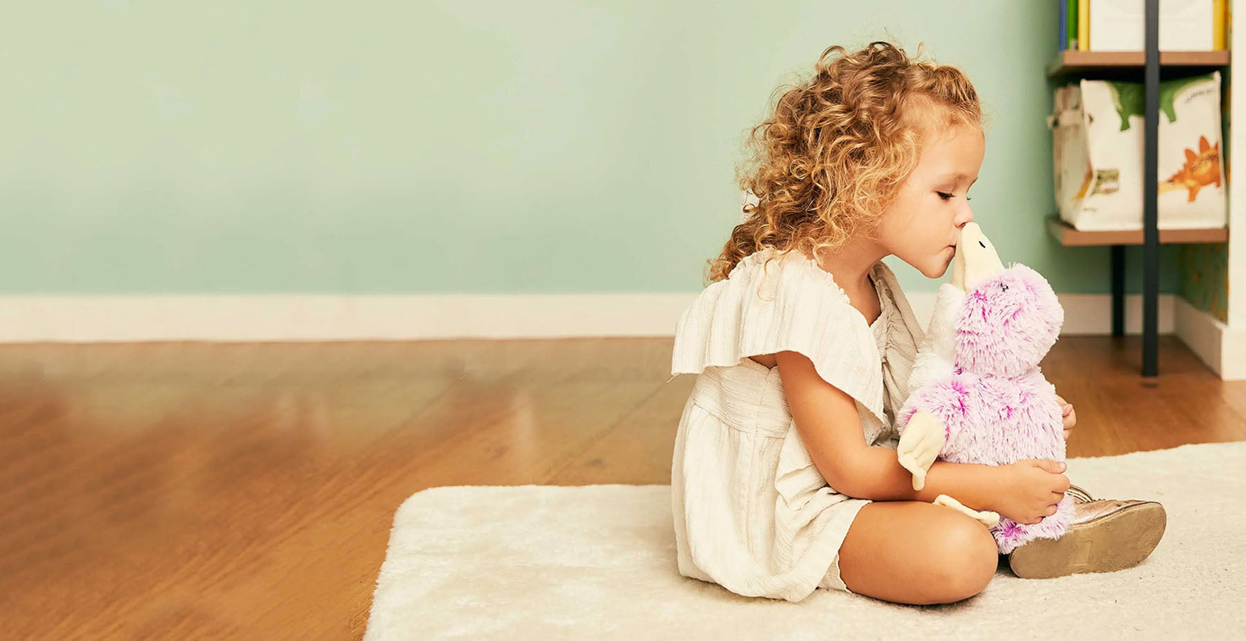 girl cuddling pink penguin heating pad stuffed animal warmies