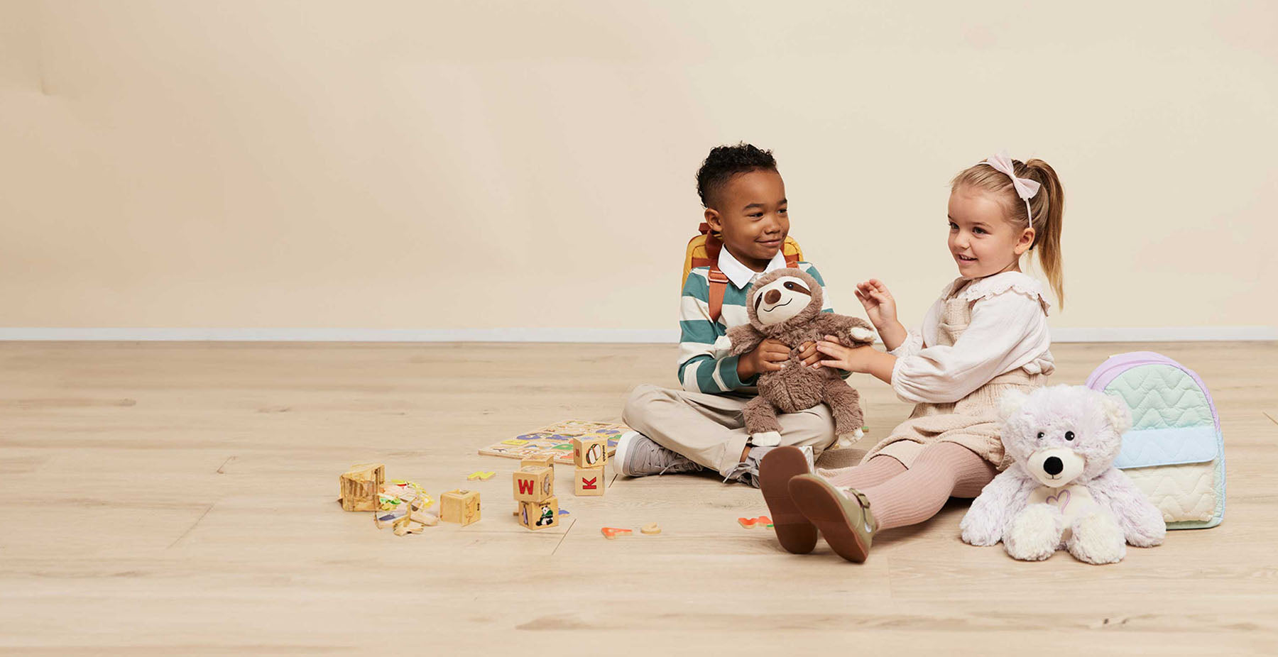 boy and girl playing with sloth and teddy bear stuffed animal warmies